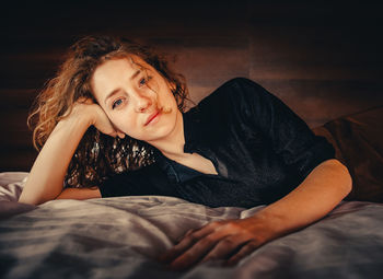 Young woman sitting on bed at home