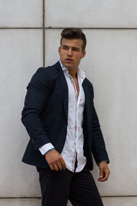 Handsome man in suit standing against wall