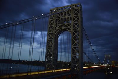 Low angle view of suspension bridge against cloudy sky