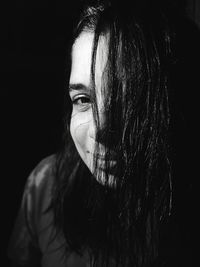 Close-up portrait of woman against black background