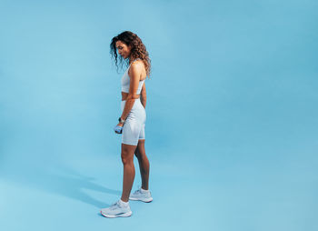 Side view of woman standing against blue background