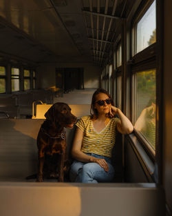 Woman and retriever dog ride a train, look out the window. traveling with a pet on public transport