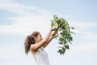 Woman standing by plant against sky