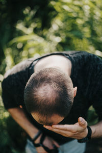 Man touching forehead while standing by plants