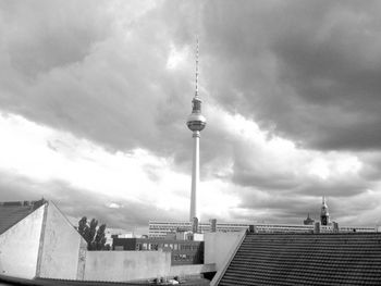 Low angle view of communications tower against cloudy sky