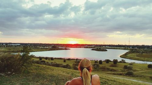 Rear view of woman at celery fields park against cloudy sky during sunset