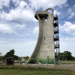 Low angle view of old tower on field against sky