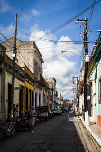 Vehicles on road amidst buildings in city against sky