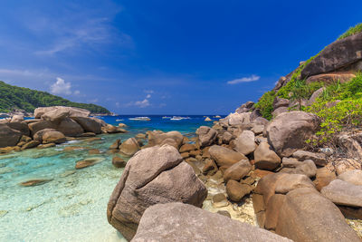 Rocks by sea against blue sky