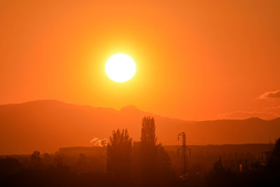 Scenic view of silhouette mountains against orange sky