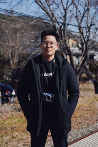 Portrait of young man standing by bare tree