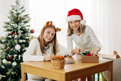 Two charming girls write greetings and wishes to friends and relatives on christmas eve 