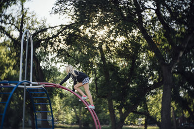 Side view of girl playing on monkey bars at park