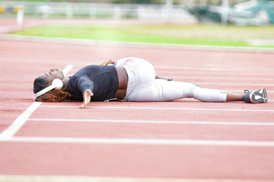 Sportswoman doing stretching exercise while lying down on runner track