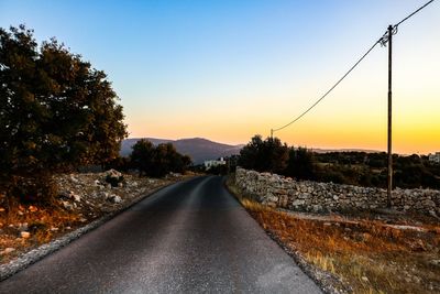 Empty road along landscape at sunset