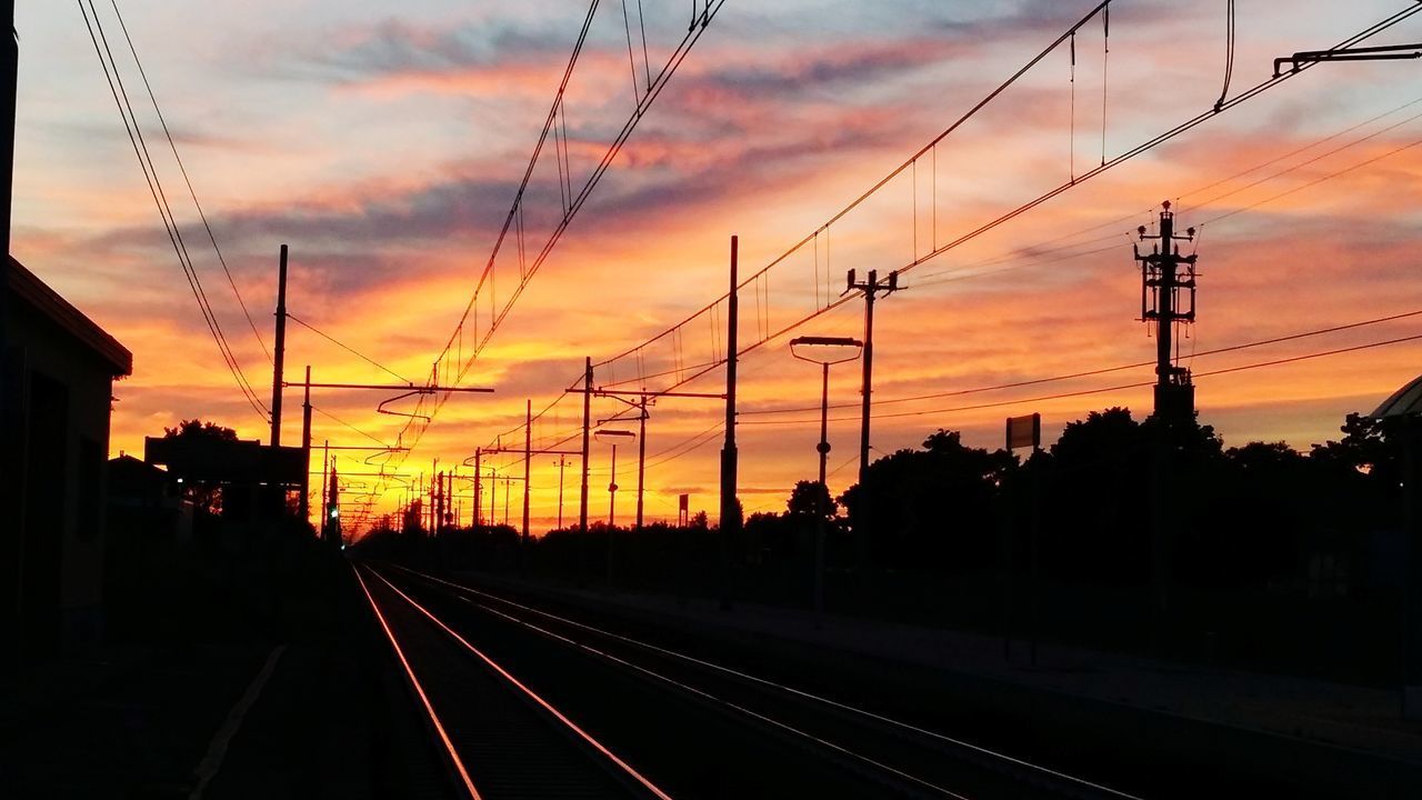 RAILROAD TRACKS AGAINST ORANGE SKY