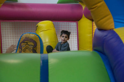 Portrait of boy sitting at bouncy castle