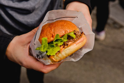 Midsection of person holding hamburger at market