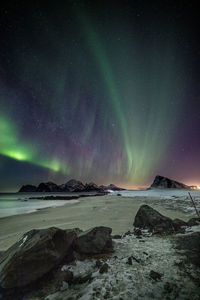 Scenic view of aurora polaris below beach against sky at night