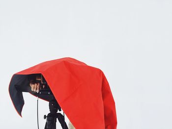 Woman photographing red umbrella against clear sky