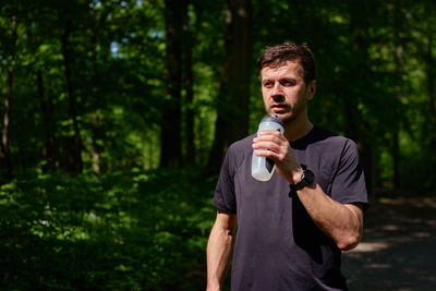 Portrait of smiling young woman standing against trees