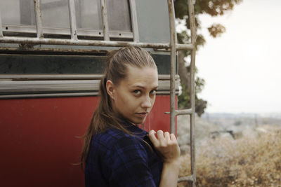 Side view portrait of young woman standing by vehicle