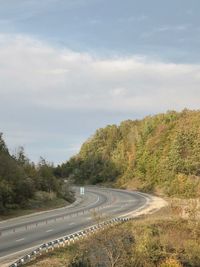 Scenic view of road by trees against sky