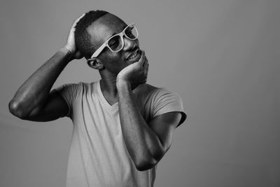 Portrait of young man wearing sunglasses standing against wall