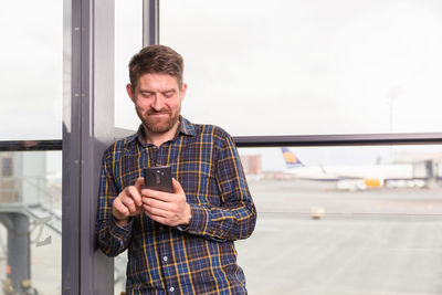 Cheerful man using smartphone in airport