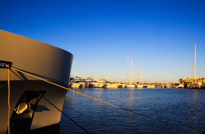 Sailboats in sea by buildings against clear blue sky