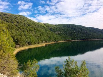 Scenic view of lake by mountains against sky