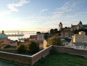 Buildings in town against sky at sunset