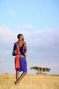 Man in traditional clothing standing on grass against sky