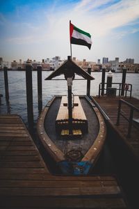 Flag on wooden post in sea against sky