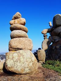 Stack of stones on rock against clear blue sky