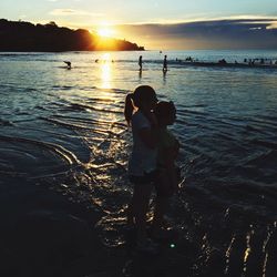 Silhouette of people on beach at sunset