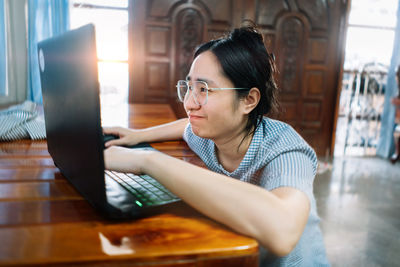 Portrait of woman using phone while sitting on table