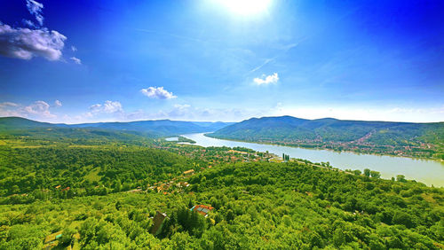 Scenic view of river amidst green landscape against blue sky