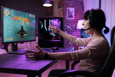 Side view of happy woman playing game at office