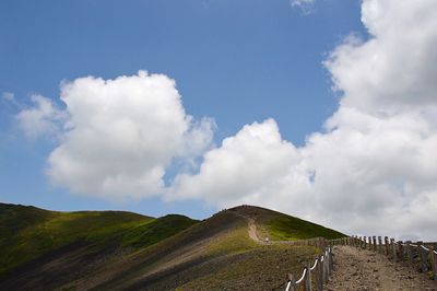 Trail leading towards green mountains against sky