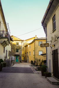 Road amidst buildings in town against clear sky