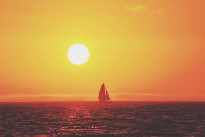 Sailboat sailing on sea against sky during sunset