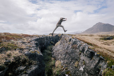 Side view of woman on rock against sky