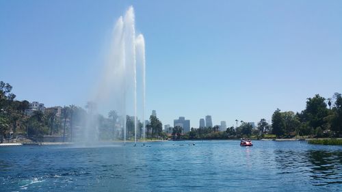 Fountain in lake against clear sky at echo park