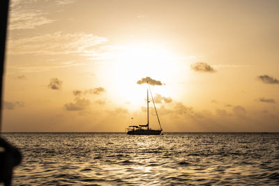 Silhouette sailboat in sea against sky during sunset