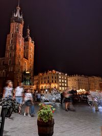 People on illuminated street amidst buildings in city at night