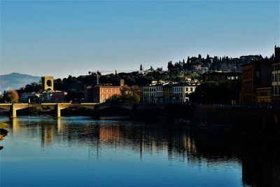 River by illuminated buildings against clear blue sky