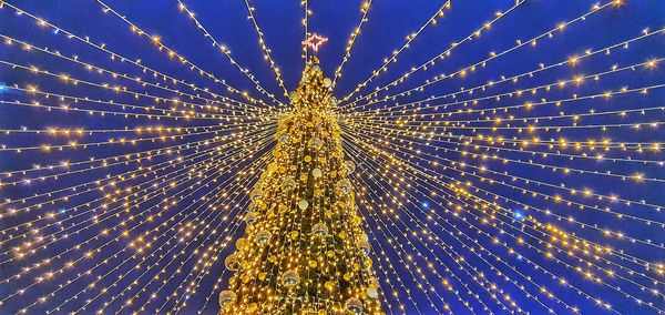 Low angle view of illuminated christmas tree against sky at night