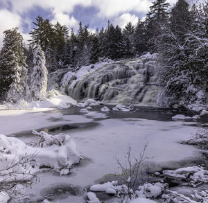 Scenic view of waterfall against sky during winter