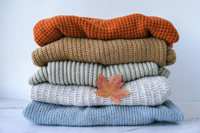 Stack of cozy knitted warm sweater with autumn fall maple leaf. sweaters in retro style. orange 